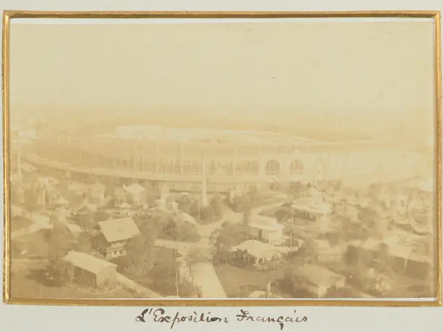 The image shows an old photo of a stadium in the middle of a city, surrounded by buildings, trees,...