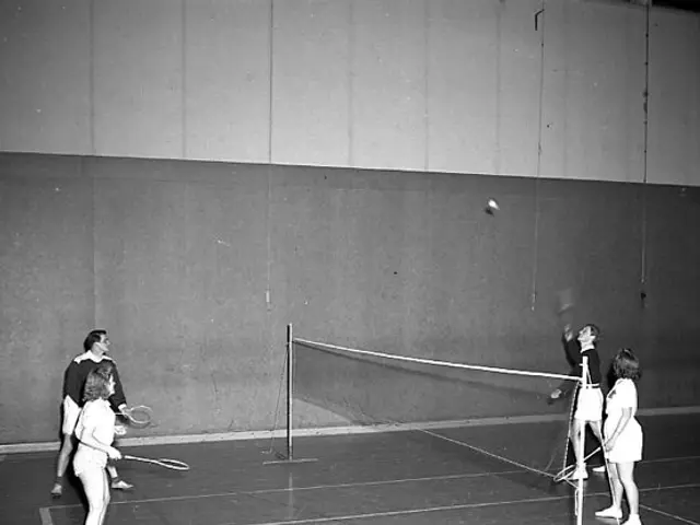 The image shows a group of people playing badminton on a court, with a net in the middle and a wall...