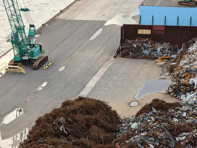 The image shows an aerial view of a large pile of trash next to a body of water, with cranes and...