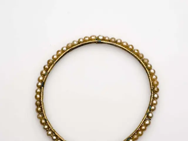 The image shows a gold beaded bangle bracelet on a white background. The bracelet is made of gold...