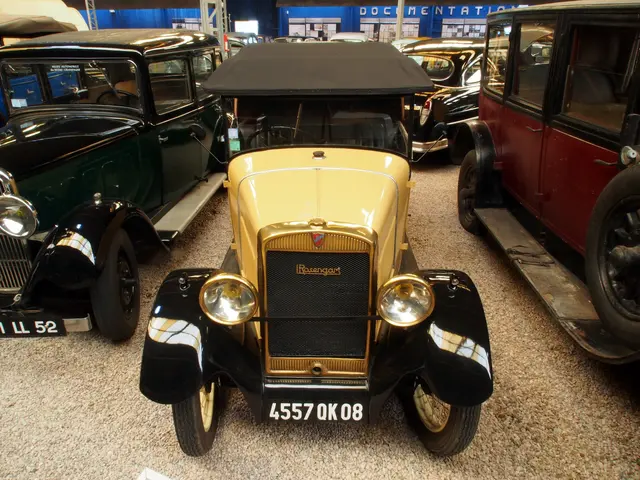 The image shows a group of old cars parked in a garage, with a wall in the background featuring...