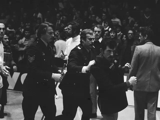 The image shows a group of men standing on top of a basketball court, with a crowd of people...