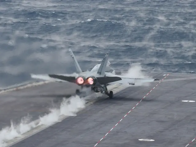 The image shows a fighter jet taking off from an aircraft carrier in the middle of the ocean, with...
