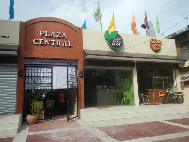 The image shows a plaza central in Cebu City, Philippines. It features buildings, motorbikes,...