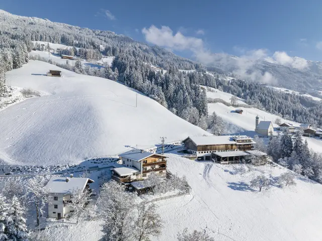 The image shows a picturesque winter scene of a small town nestled in the middle of a snowy...