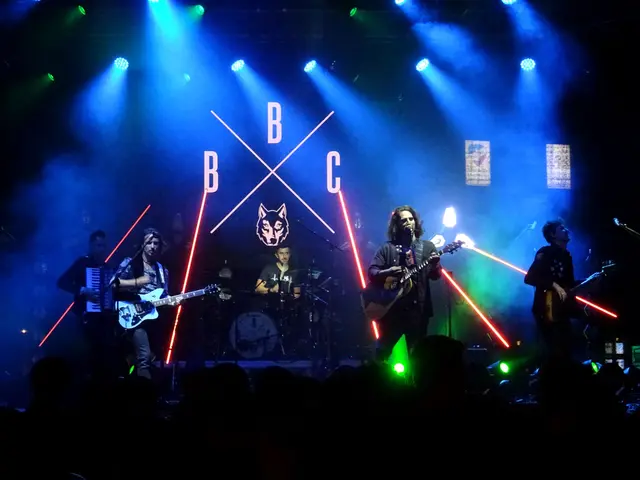 The image shows a group of people on stage playing guitars and singing, with mics and stands set up...