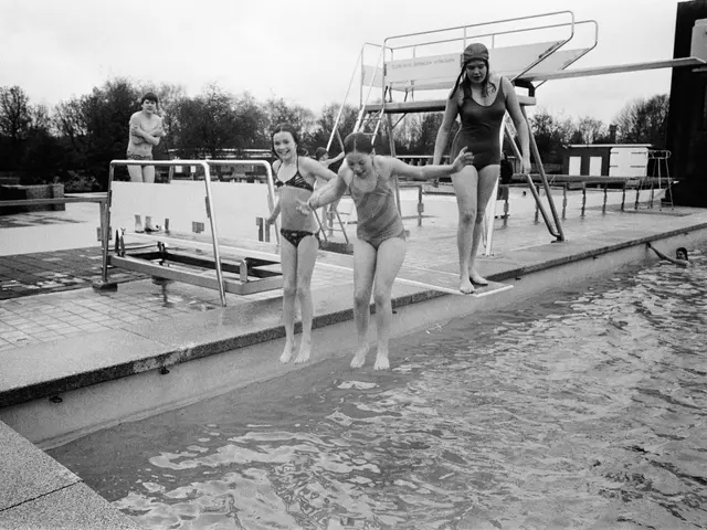 The image shows a group of three women jumping into a swimming pool. The pool is surrounded by...