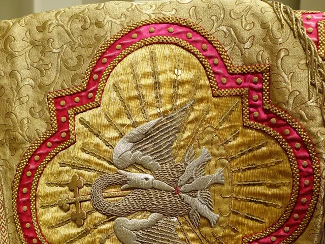 The image shows a close up of a priest's vestment with a gold and red design on it, set against a...