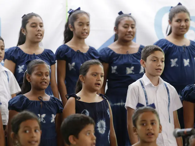 The image shows a group of children standing next to each other in front of a microphone, with a...