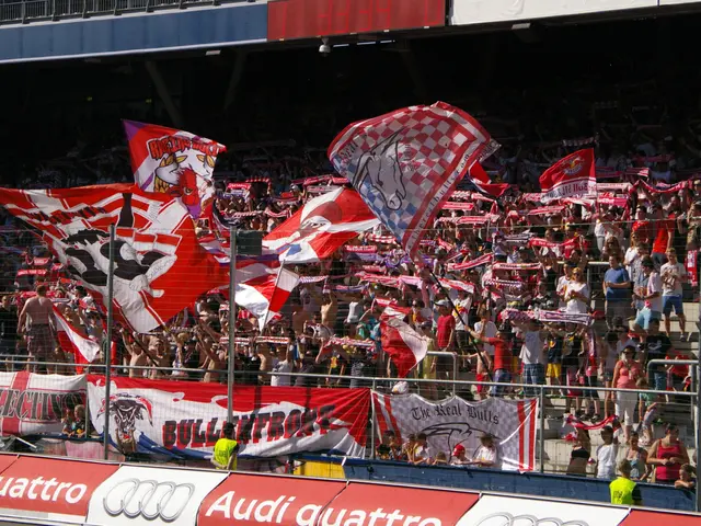 The image shows a large crowd of people in a stadium, some of them holding flags and banners with...