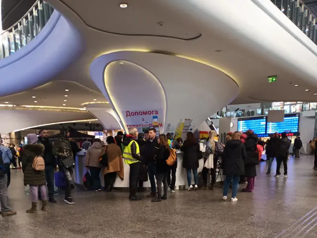 The image shows a large group of people standing in an airport terminal, with some of them holding...