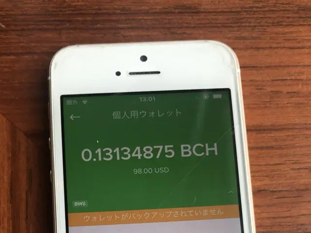 The image shows a white iPhone sitting on top of a wooden table, with a screen displaying text and...