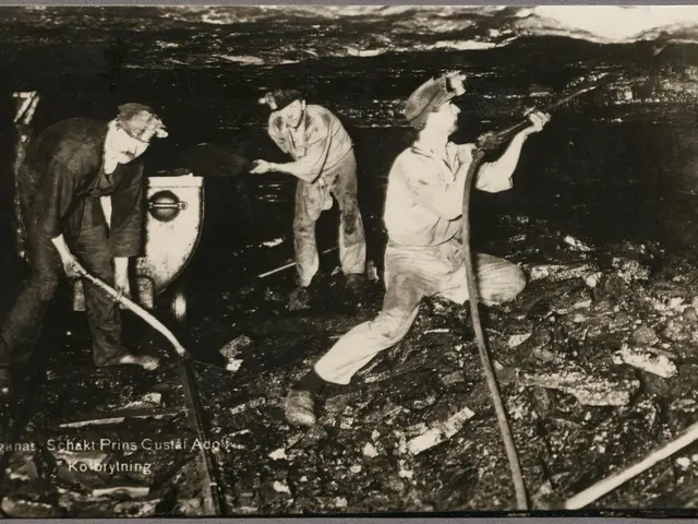 The image shows a black and white photo of three men working in a coal mine. They are standing on...