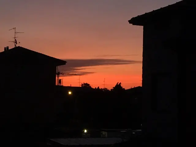 The image shows a view of a city at sunset from the roof of a building. I can see a number of...