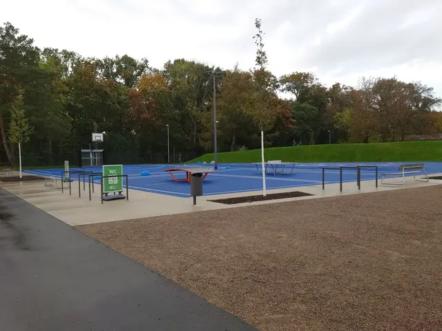 The image shows a park with a basketball court in the middle of it, surrounded by street light...