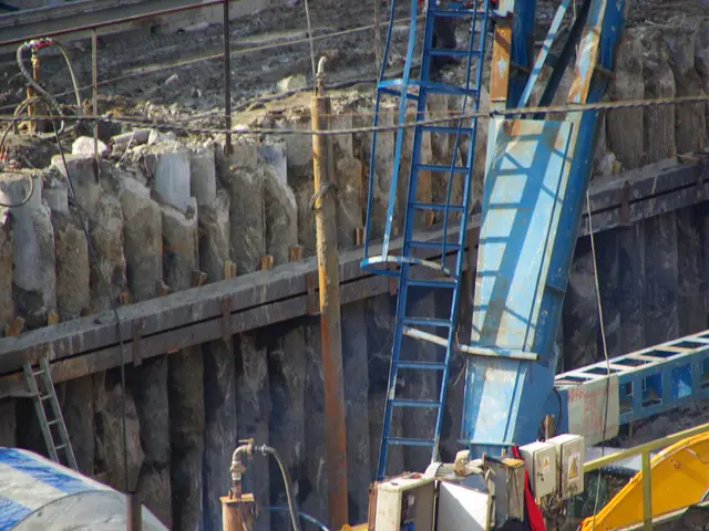 The image shows a construction site with a large crane in the middle of it, surrounded by ladders,...