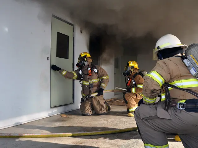 The image shows a group of firefighters wearing helmets, gloves, and oxygen cylinders, working to...