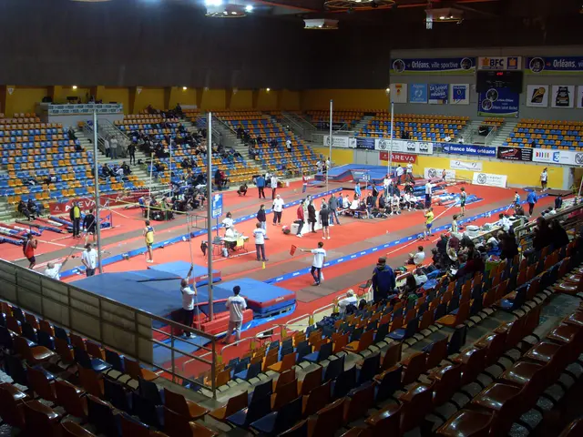The image shows a large indoor stadium filled with lots of people, some standing and some sitting...