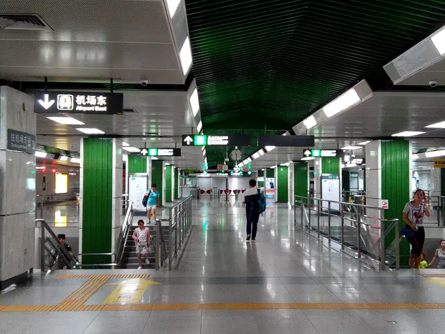 The image shows a subway station with people walking through it. There are escalators with...
