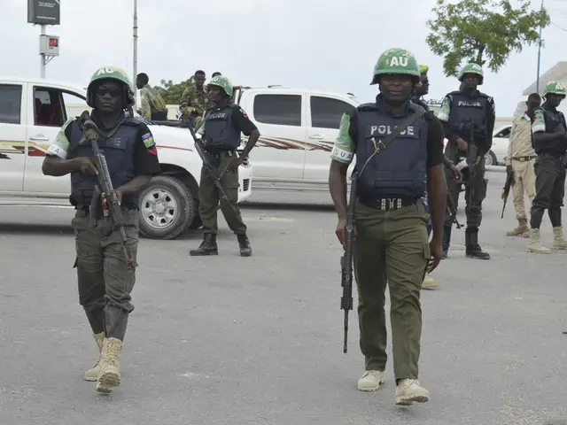 The image shows a group of police officers walking down a street, wearing helmets and holding guns....