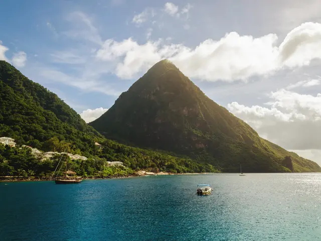 The image shows a boat in the ocean with a mountain in the background, surrounded by lush green...