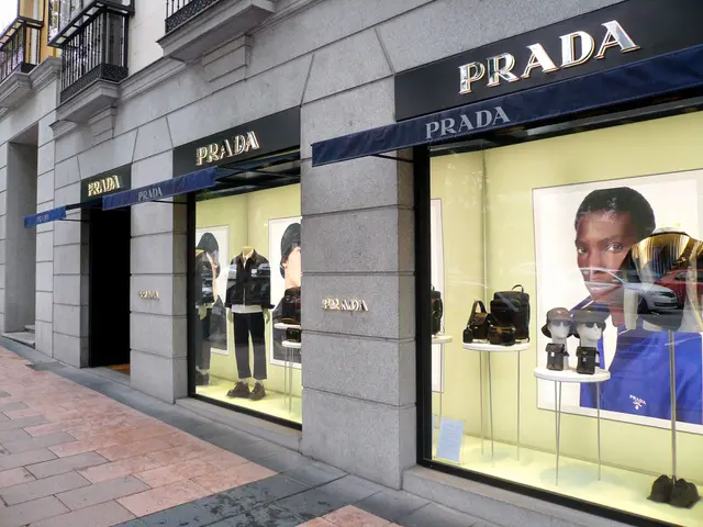 The image shows a Prada store on the corner of a street, with mannequins wearing dresses, bags, and...