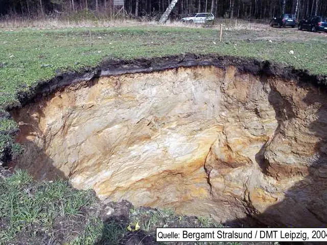 The image shows a large sinkhole in the middle of a grassy field, with two cars parked on the right...