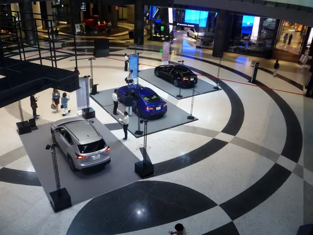 The image shows a large room filled with lots of cars on display, with a group of people standing...