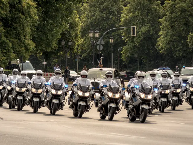 The image shows a group of police officers riding motorcycles down a street lined with trees, light...