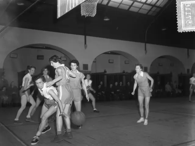 The image shows a group of young women playing basketball in a gymnasium, with a basketball net at...