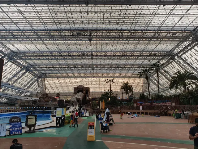 The image shows a group of people standing in front of a large indoor swimming pool surrounded by...