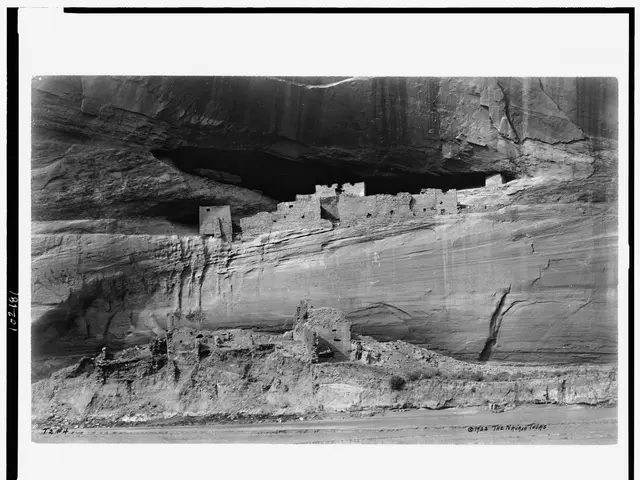 The image shows a black and white photo of a cliff dwelling in Mesa Verde National Park, Colorado....