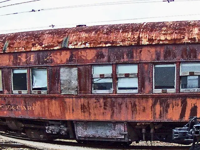 In the center of the image we can see train on railway track. In the background we can see wires...
