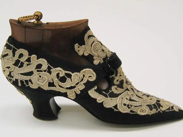 The image shows a pair of black and gold shoes with intricate embroidery on them, set against a...