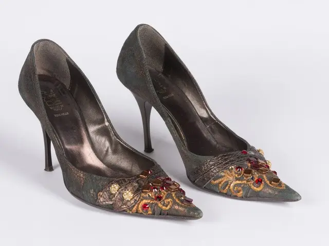 The image shows a pair of green high heels with gold and red crystals adorning them, set against a...
