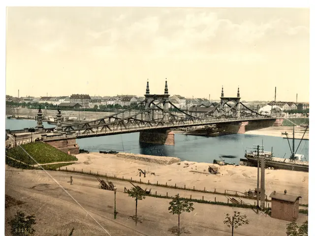 The image shows an old photo of a bridge spanning a body of water, with boats on the surface of the...