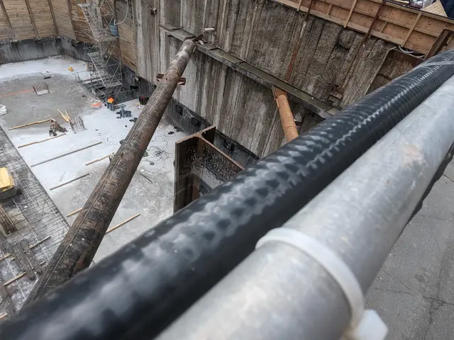 The image shows a construction site with a large metal pipe in the middle of it, surrounded by a...