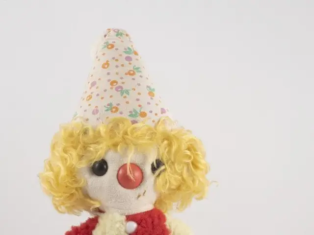 The image shows a stuffed toy clown wearing a red and white dress and a party hat, with a black...