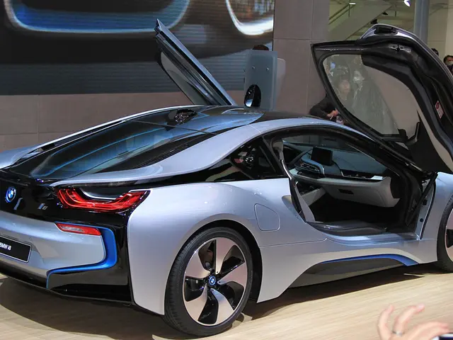 The image shows a BMW i8 concept car at the Frankfurt Motor Show, surrounded by a group of people....