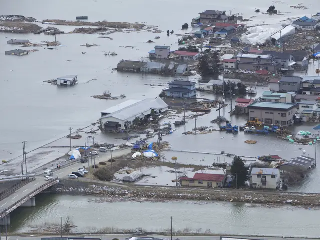 The image shows an aerial view of a flooded area in the middle of a city, with buildings, trees,...