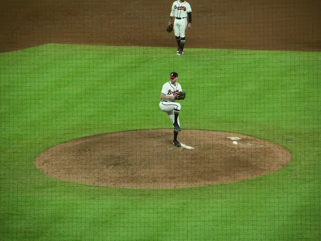 The image shows a baseball player pitching a ball on top of a field, wearing a sports uniform and...