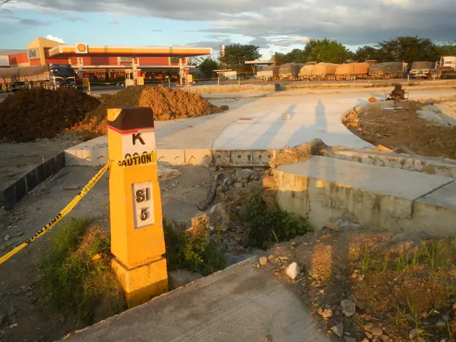 The image shows a construction site with a yellow caution sign sitting on the side of a road,...