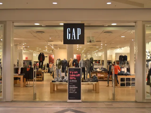 The image shows a Gap store in a mall with mannequins in the window, clothes hung on hangers,...
