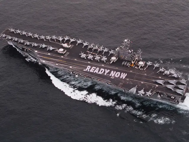 The image shows an aircraft carrier, the USS George H W Bush CVN-68, transiting the Arabian Sea. On...
