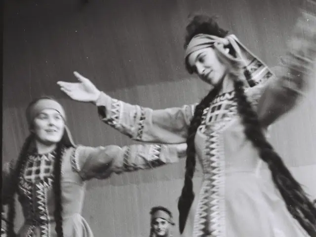 The image shows a group of women in traditional Bulgarian costumes dancing on a stage, with a vase...
