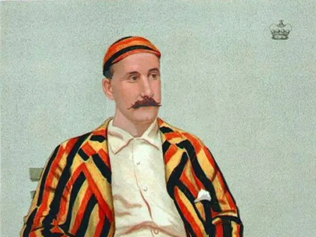 The image shows a man sitting on a bench, holding a cricket bat in his hand. He is wearing a...
