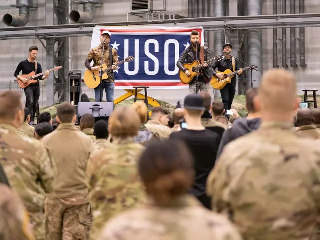 The image shows a group of soldiers standing in front of a crowd, playing guitars and singing into...