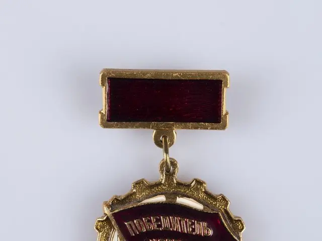 The image shows a gold medal with a red ribbon attached to it, which is a badge with text written...