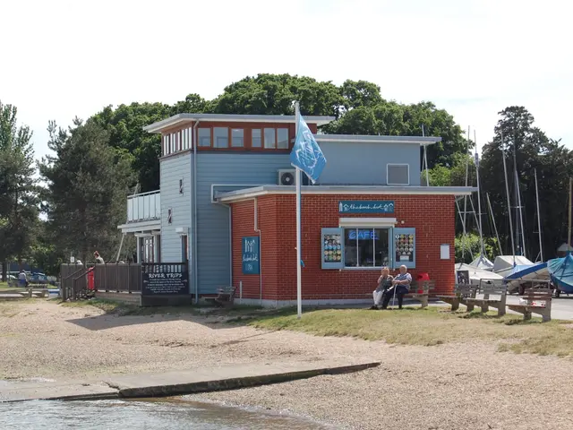 The image shows a lifeguard station on the beach with people sitting on benches in front of it....