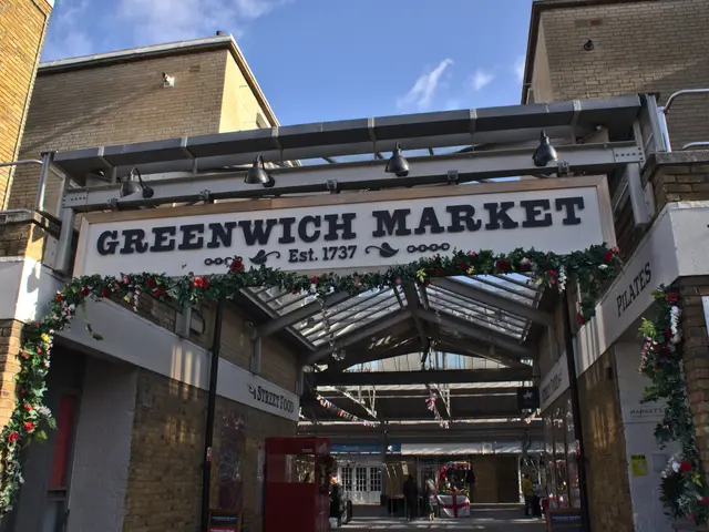 The image shows the entrance to Greenwich Market in London, England. It is an arch with text on it,...